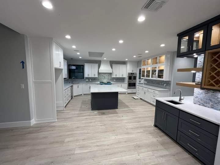 Modern white kitchen with gray island, black cabinets, and recessed ceiling lights