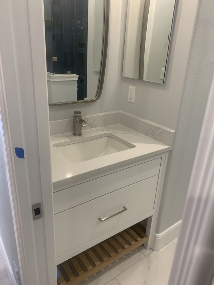 Compact white bathroom vanity with sink, mirror, and chrome faucet against light gray walls.