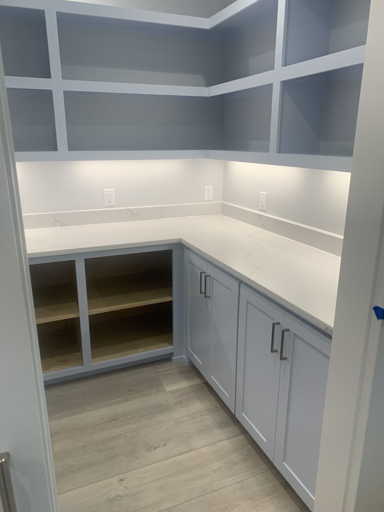 White built-in office nook with gray cabinets, open shelves, and light wood flooring