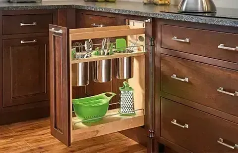 Pull-out kitchen cabinet organizer with shelves and bowls in a dark wood kitchen