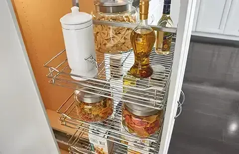 Kitchen pantry rack with jars, bottles, and a paper towel holder on wire shelves