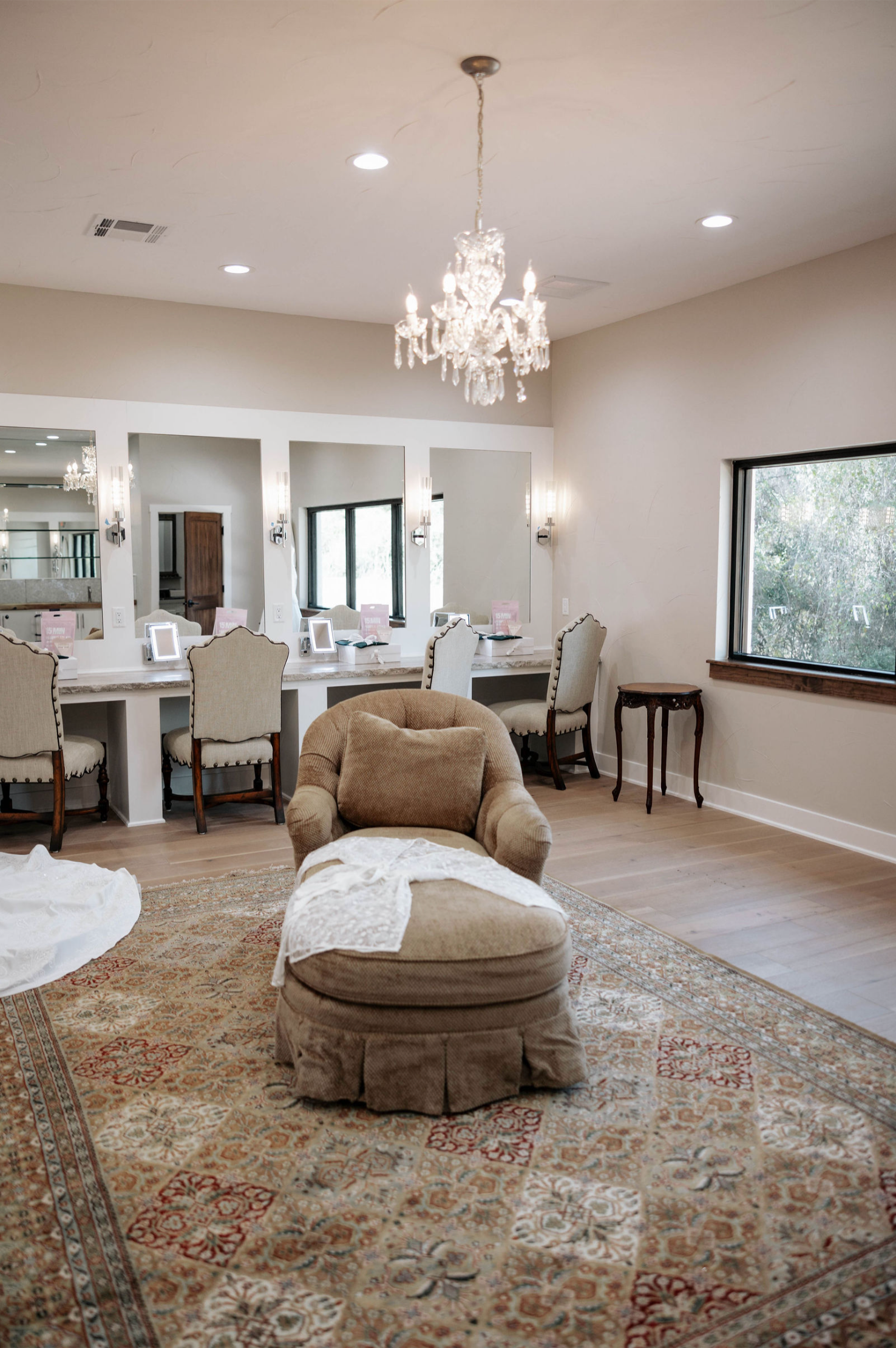 Elegant bridal suite with vanity stations, chandelier, chaise lounge, and oriental rug.