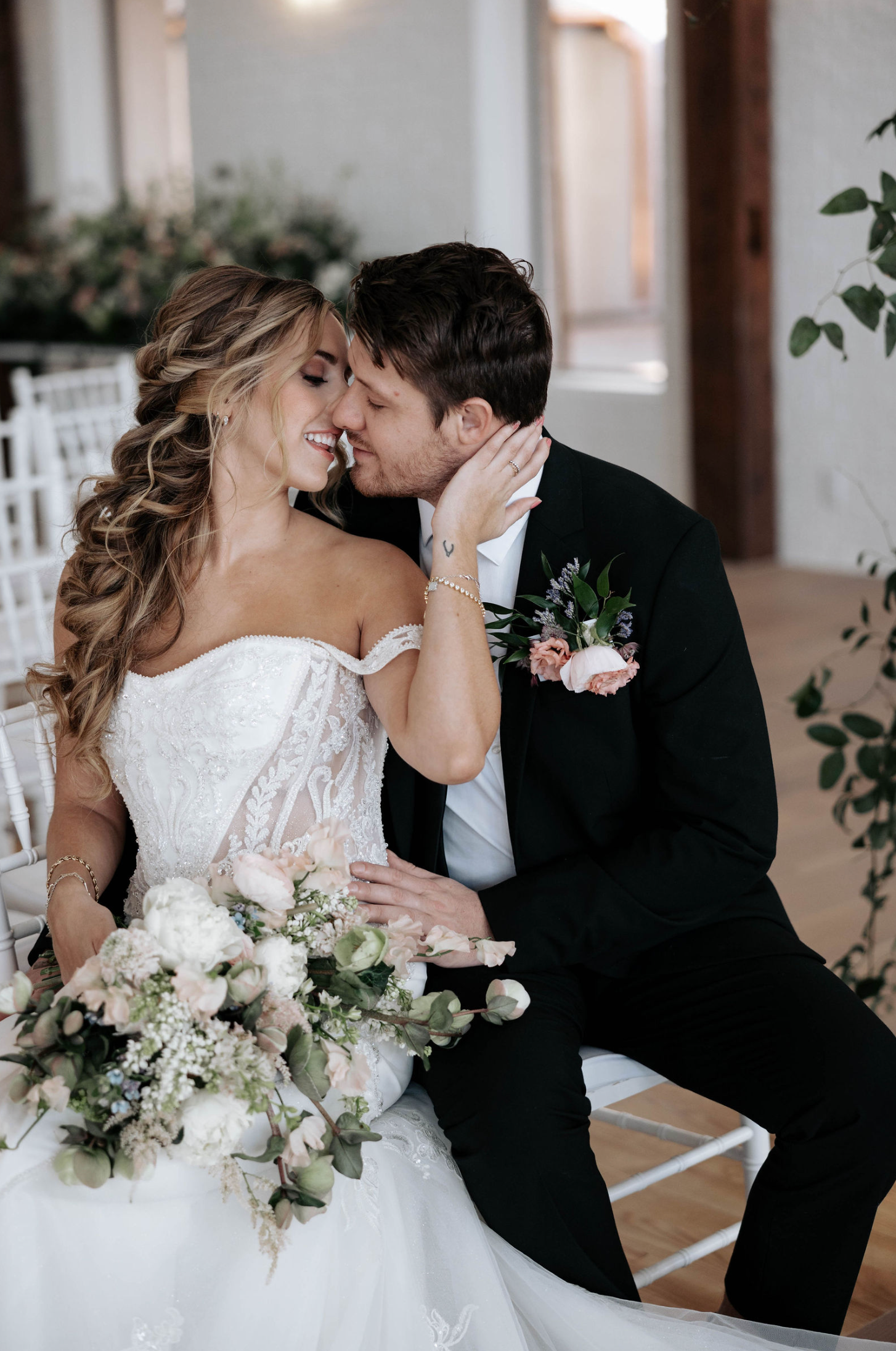 Wedding couple kissing; bride in strapless gown, groom in suit; floral bouquet.