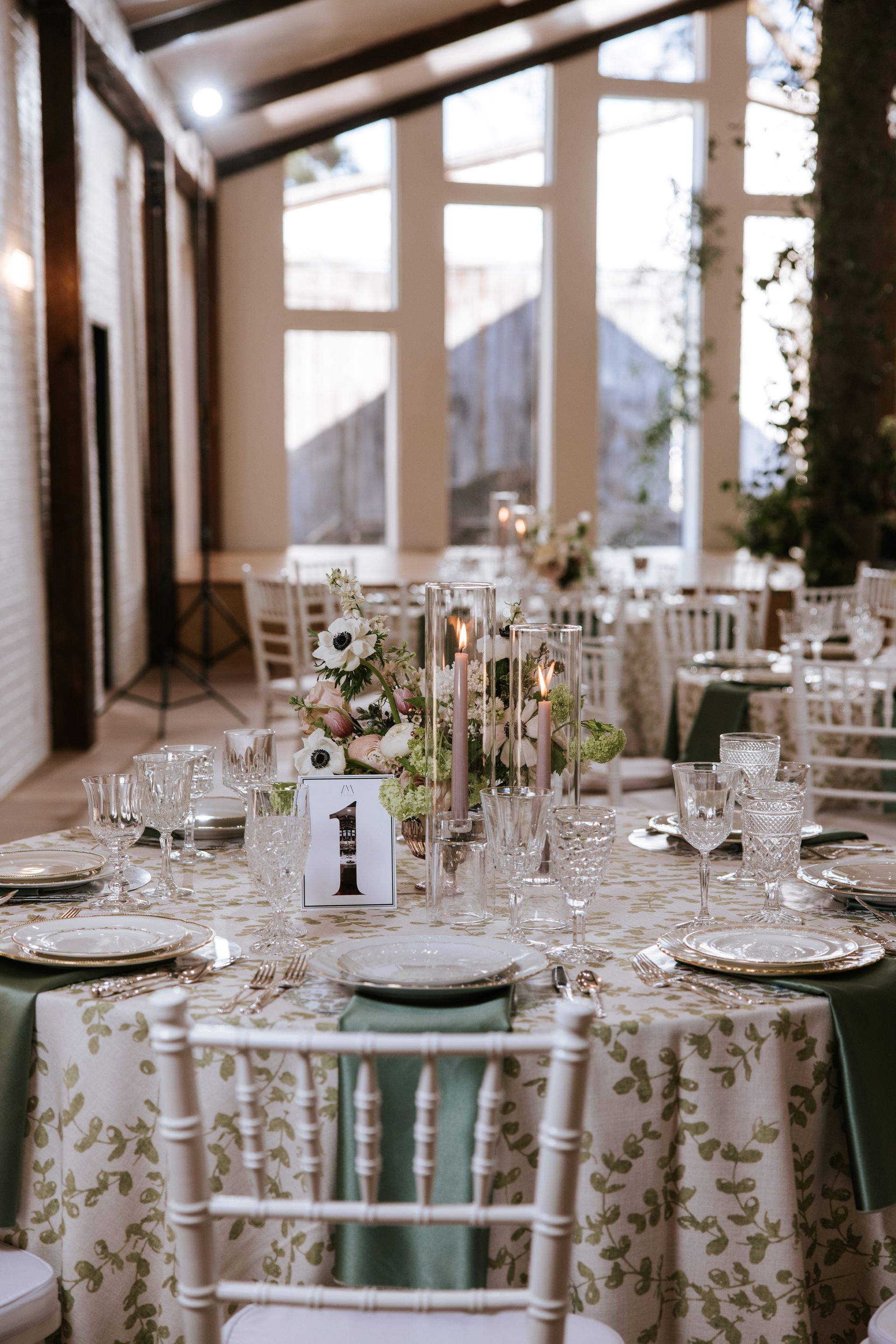 Wedding reception table set with floral centerpiece, candles, and elegant place settings.