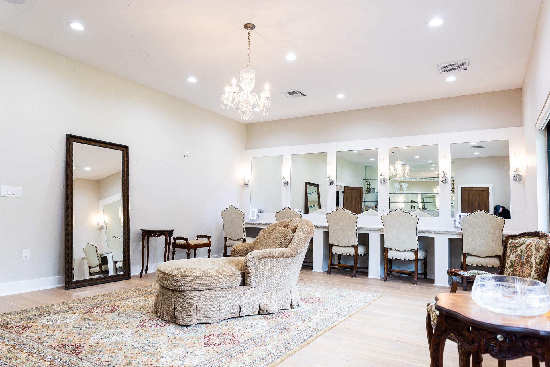 Spacious bridal suite with mirrors, vanities, and seating; a large area rug covers the floor.