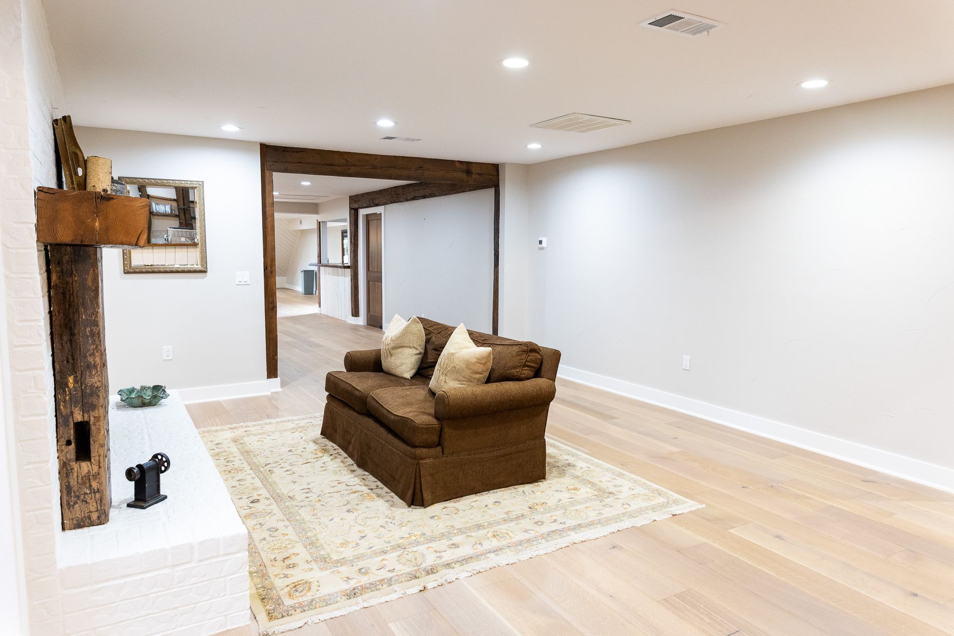 Cozy living space with brown sofa on a patterned rug, fireplace, and light wood flooring.