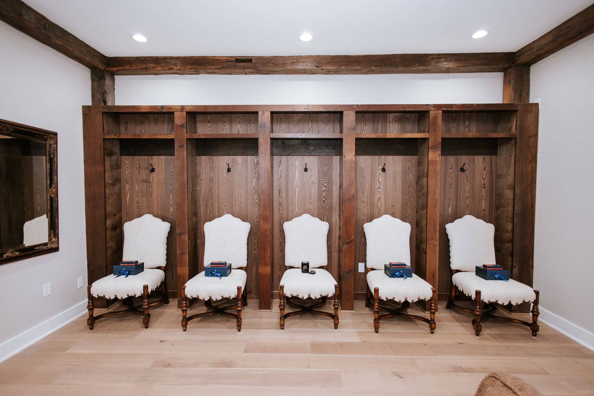 Five chairs with blue boxes sit in front of wooden lockers in a room with light wood floors.