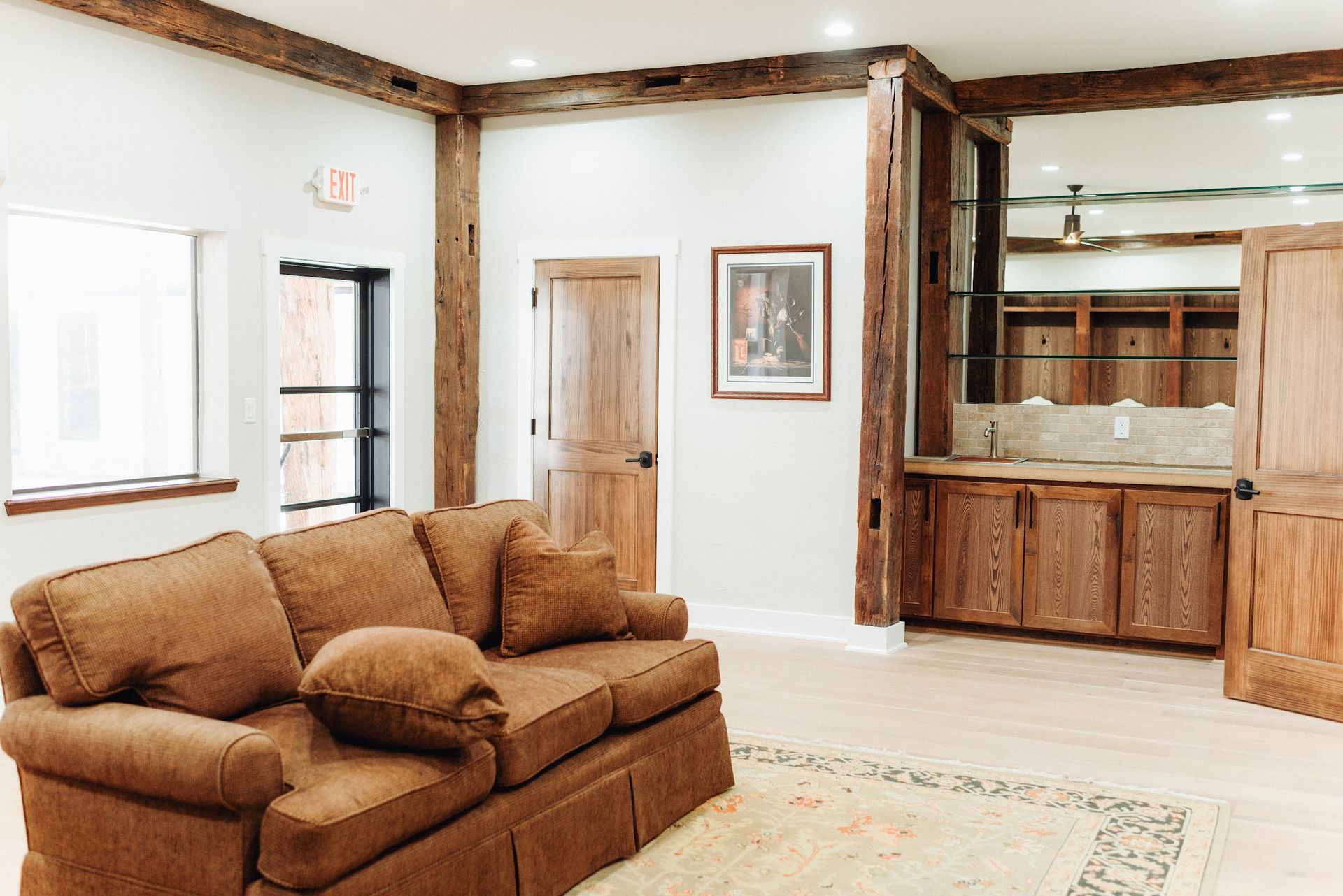 Cozy room with a brown couch, wooden beams, a bar, and a framed picture.