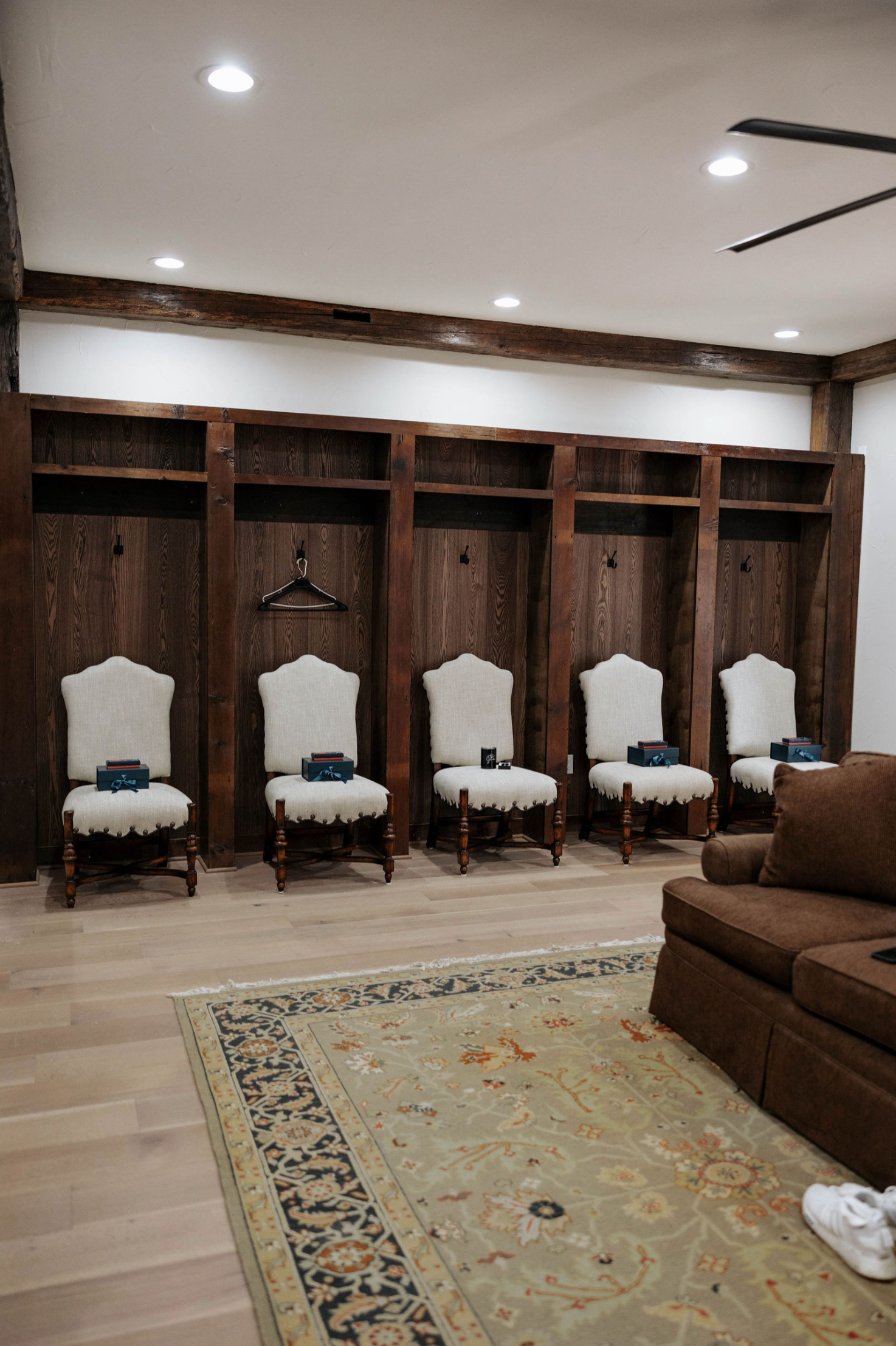 Rustic dressing room with wooden lockers, upholstered chairs, and a rug.