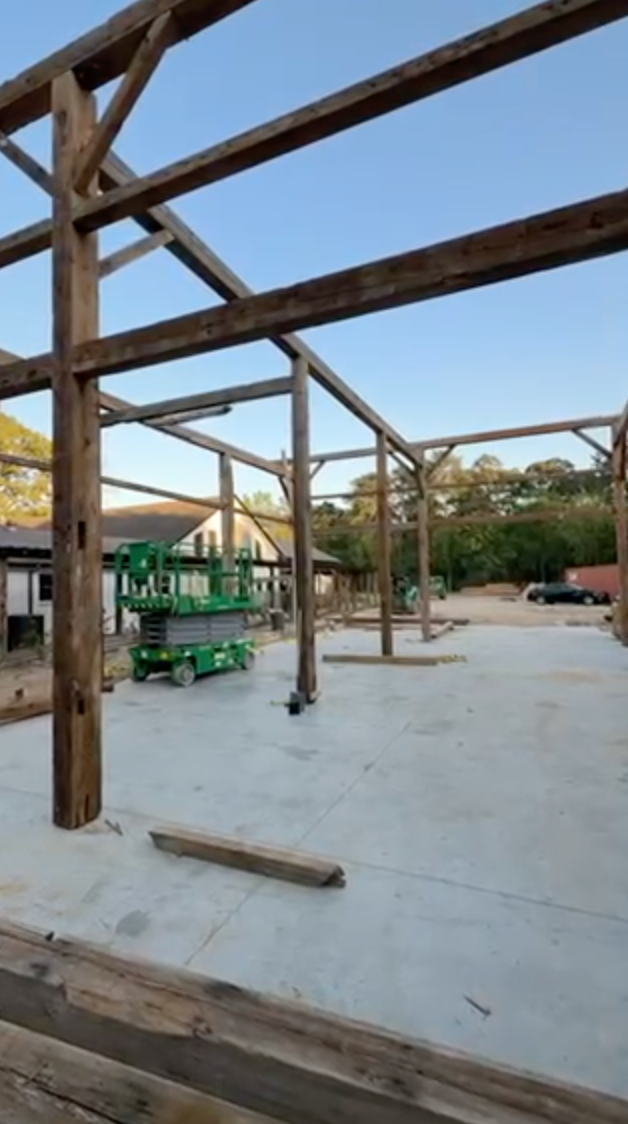 Construction site with wooden frame. Concrete floor. Green lift. Clear sky.