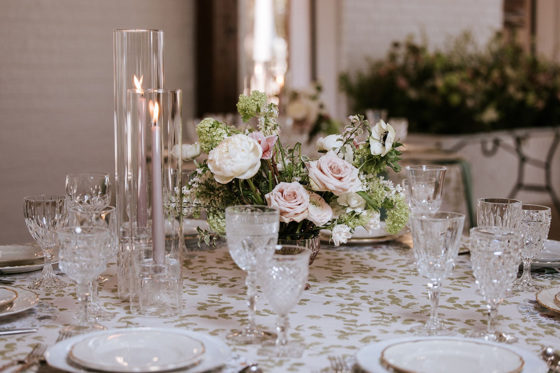 Wedding table setting with floral centerpiece, candles, and elegant glassware.
