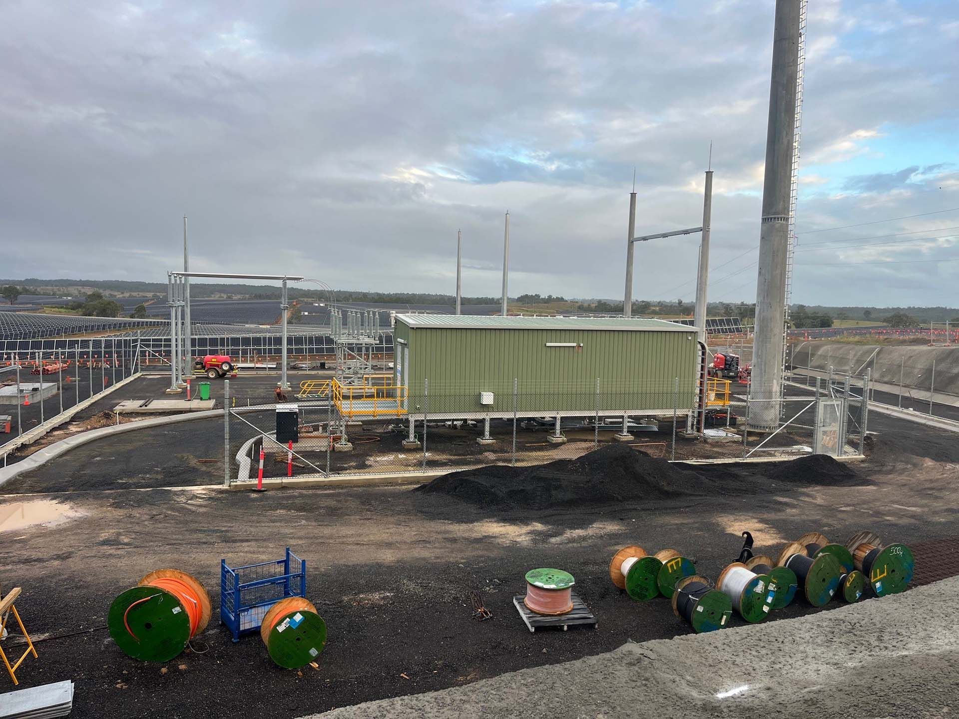 Construction site with a large green container, utility poles, and spools of cable
