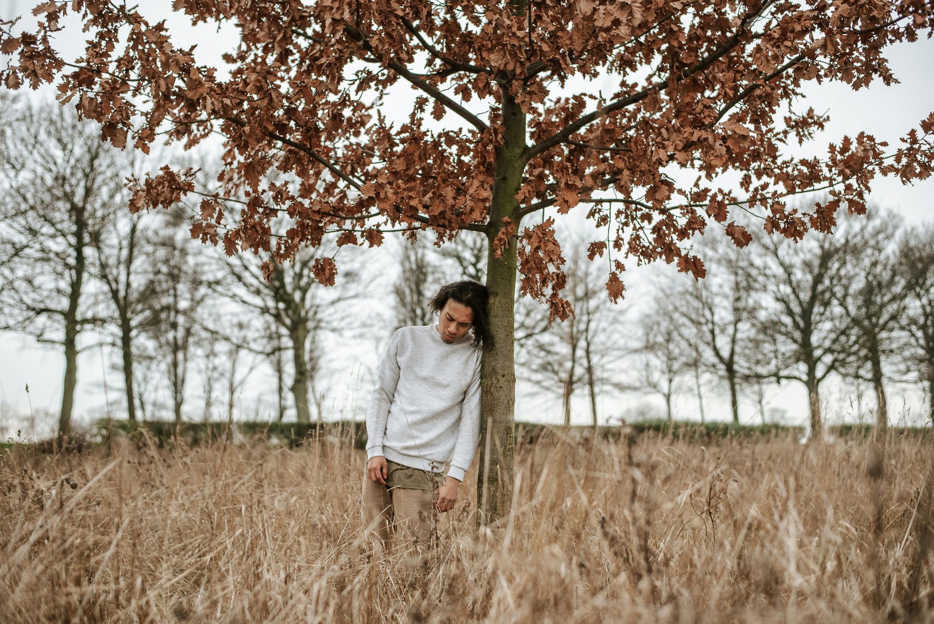 Person surrounded by autumn leaves, symbolising the loss of a loved one and the experience of grief.