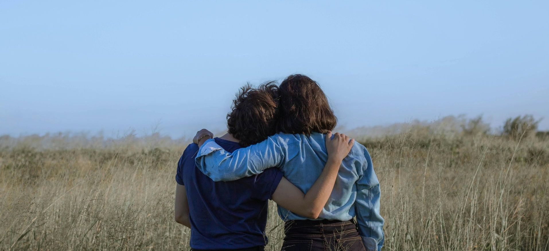 Two people supporting each other with their arms around each other.