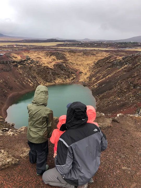 man and  children are looking at a lake.