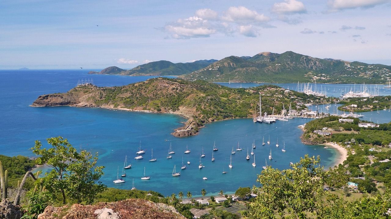 Blue ocean bay with sailboats; green hills and blue sky. Antigua