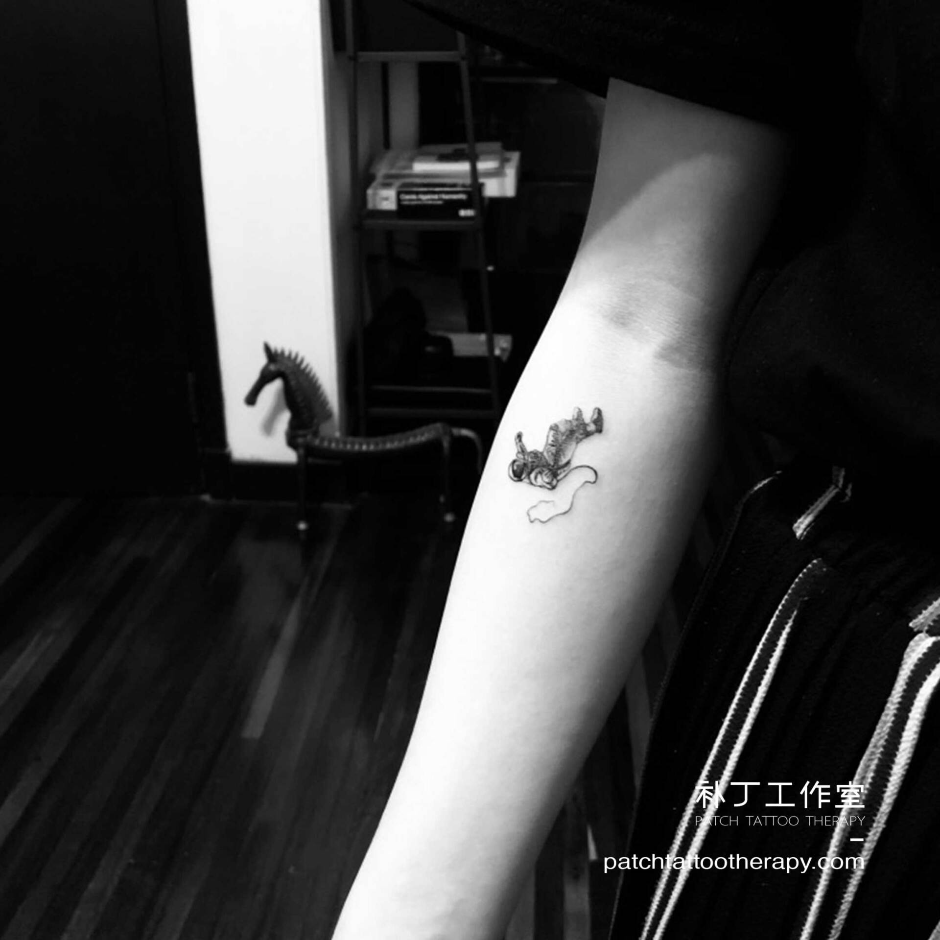 Inner forearm tattoo of a falling astronaut in micro mini style designed by Jingxi Gu at Patch Tattoo Therapy - angle 1