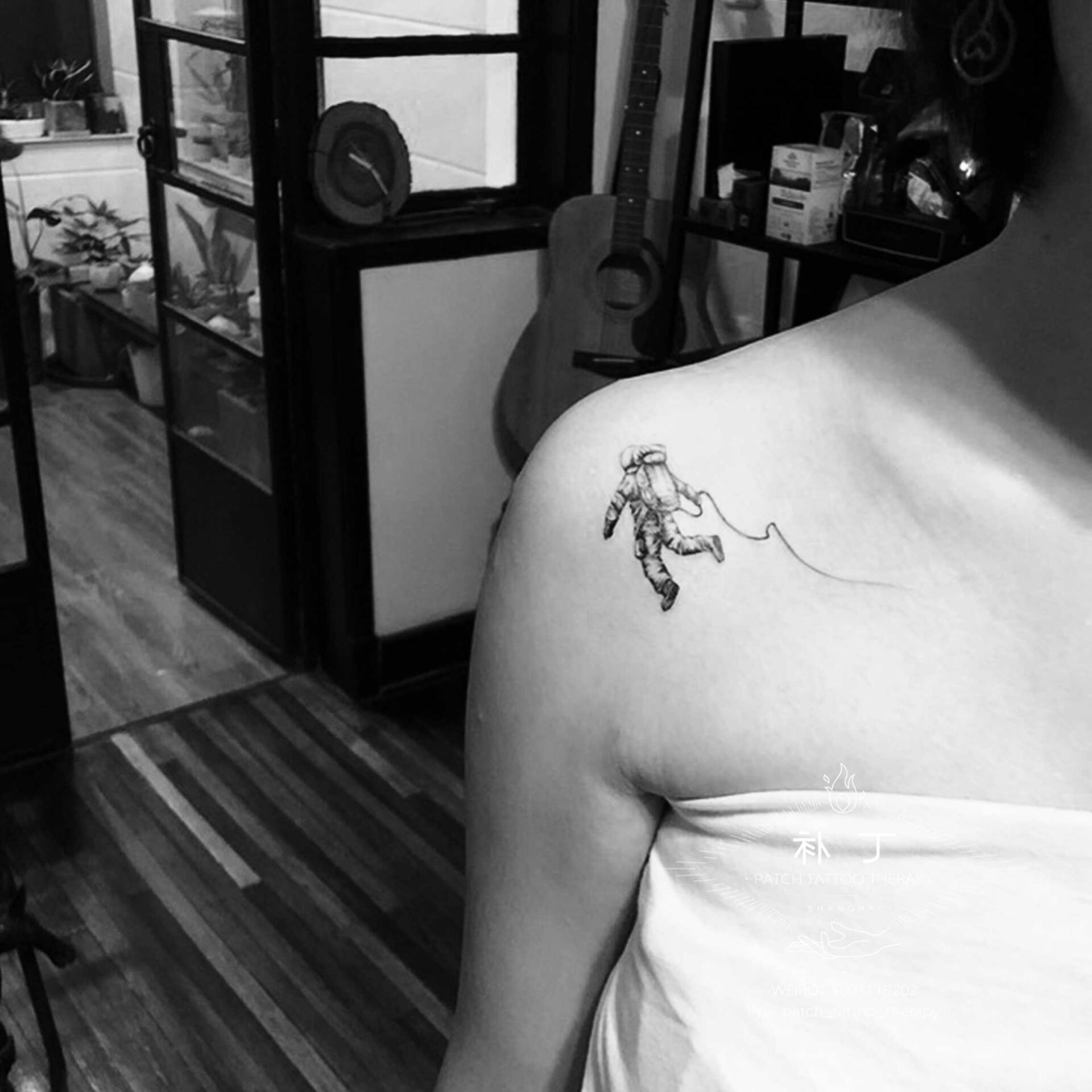 Shoulder blade tattoo of a floating astronaut in micro mini style designed by Jingxi Gu at Patch Tattoo Therapy