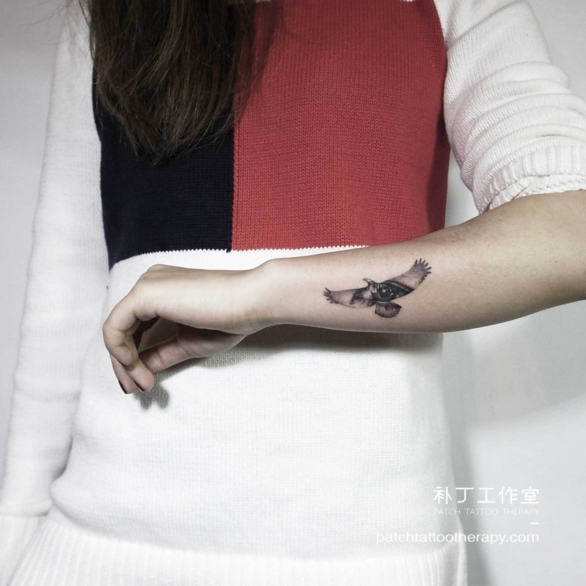 Outside forearm tattoo of an eye in the shape of a bird in micro mini style designed by Jingxi Gu at Patch Tattoo Therapy