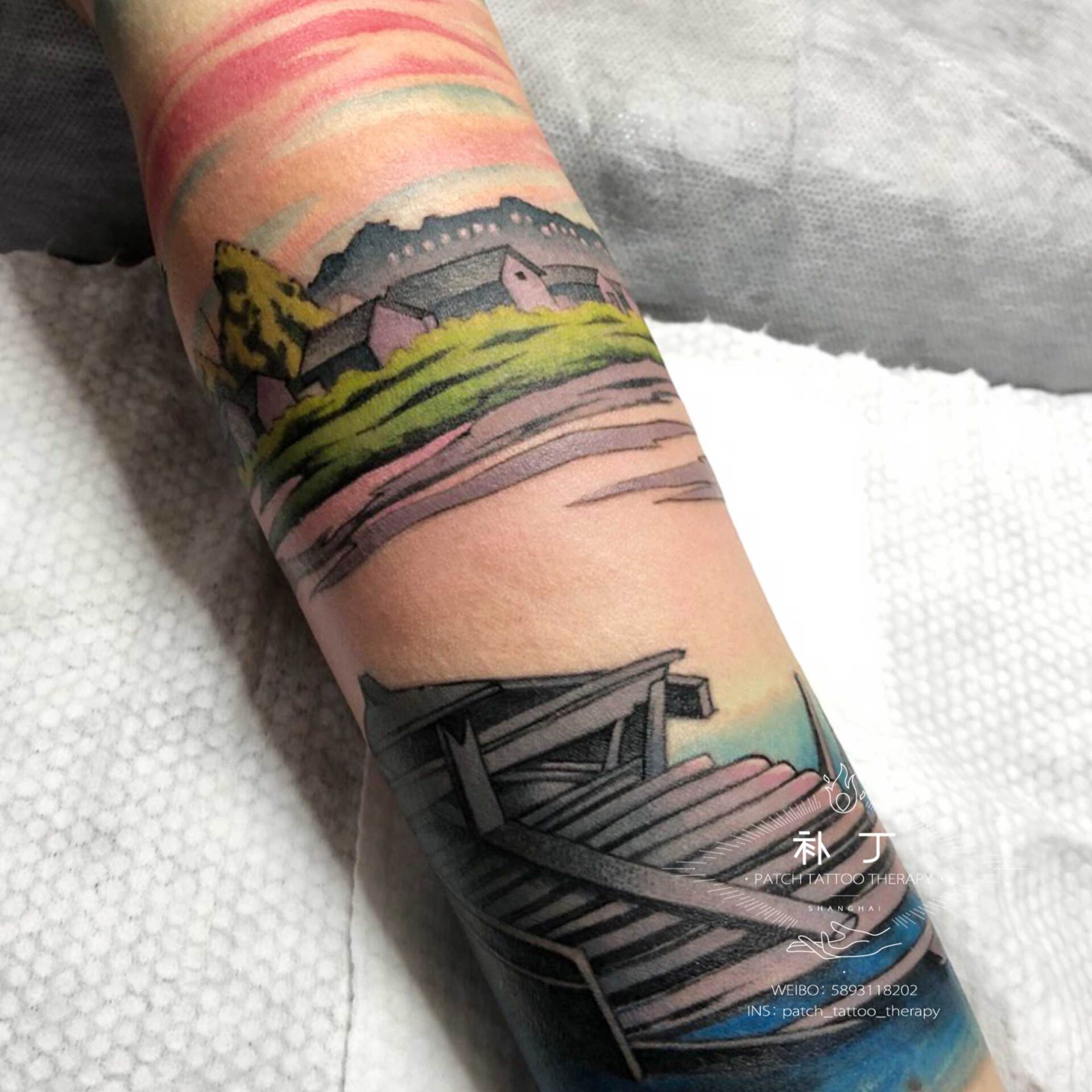 Forearm sleeve tattoo of a peaceful scene featuring a boat, lake, ducks, and rustic buildings in Japanese styled color designed by Jingxi Gu at Patch Tattoo Therapy - angle 3