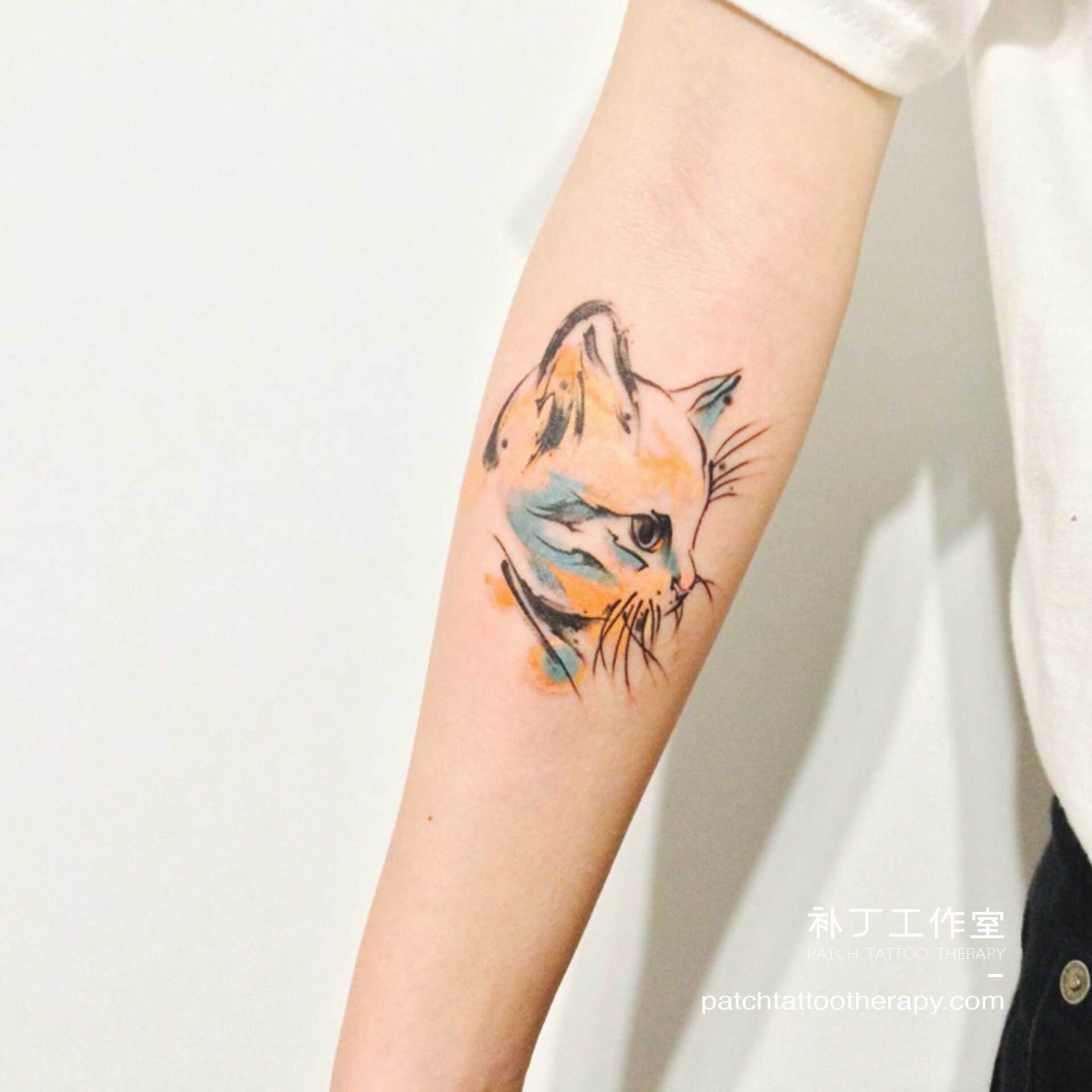 Inner forearm tattoo of a cat face in abstract color designed by Jingxi Gu at Patch Tattoo Therapy