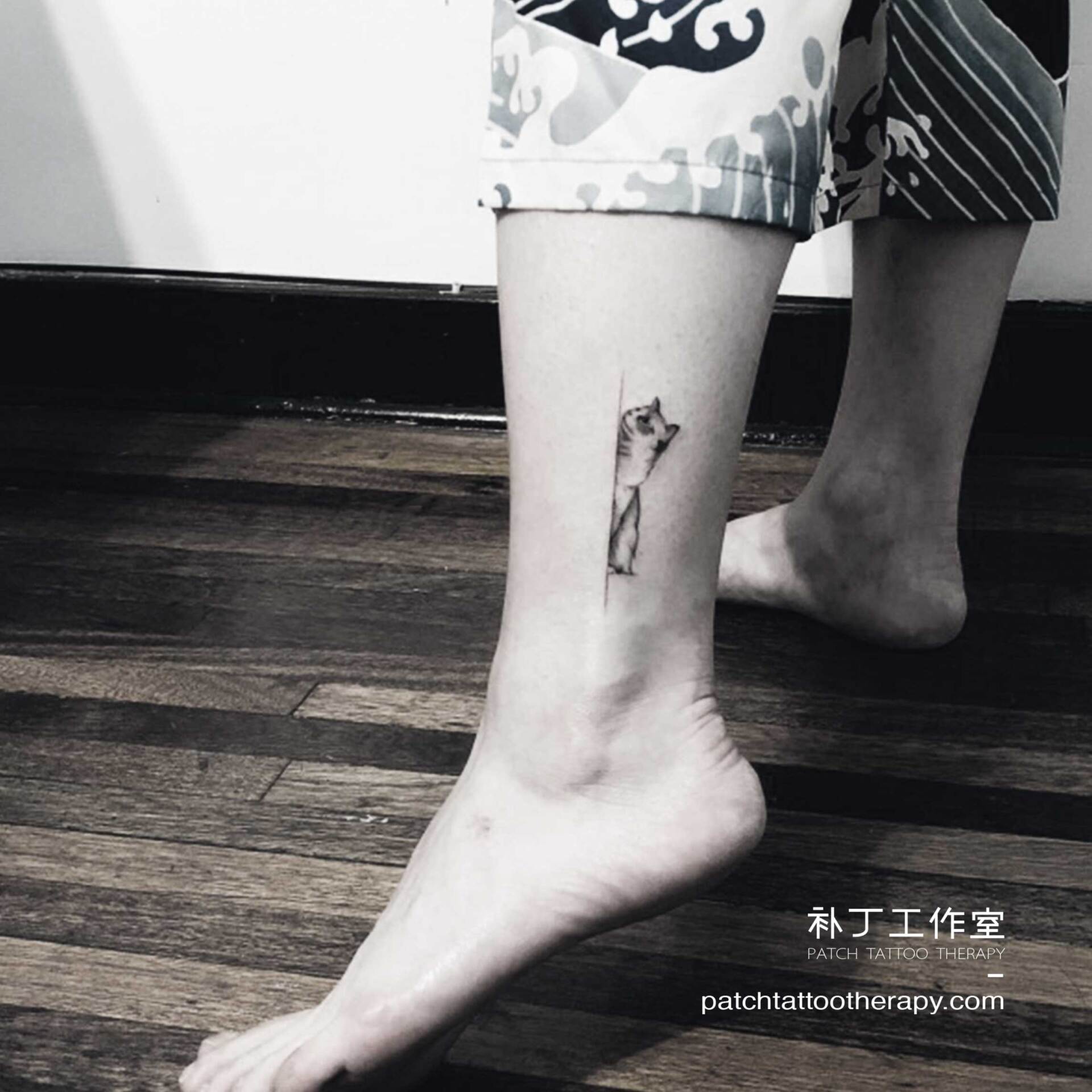 Ankle tattoo of a peeping cat in micro mini style designed by Jingxi Gu at Patch Tattoo Therapy