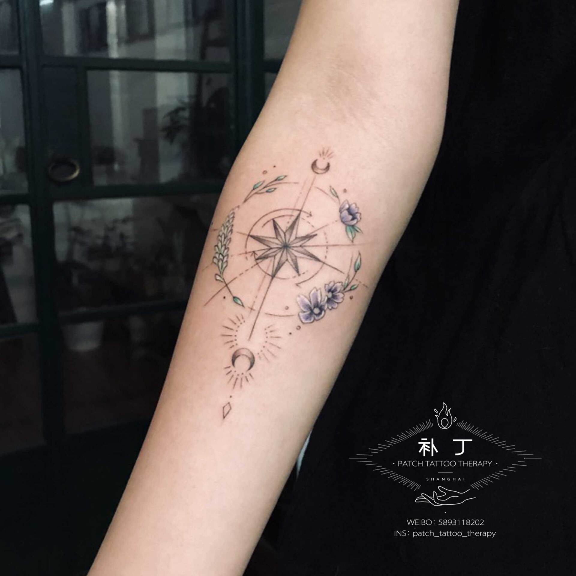 Inner forearm tattoo of a compass between moons and flowers in geometric style designed by Jingxi Gu at Patch Tattoo Therapy - angle 1