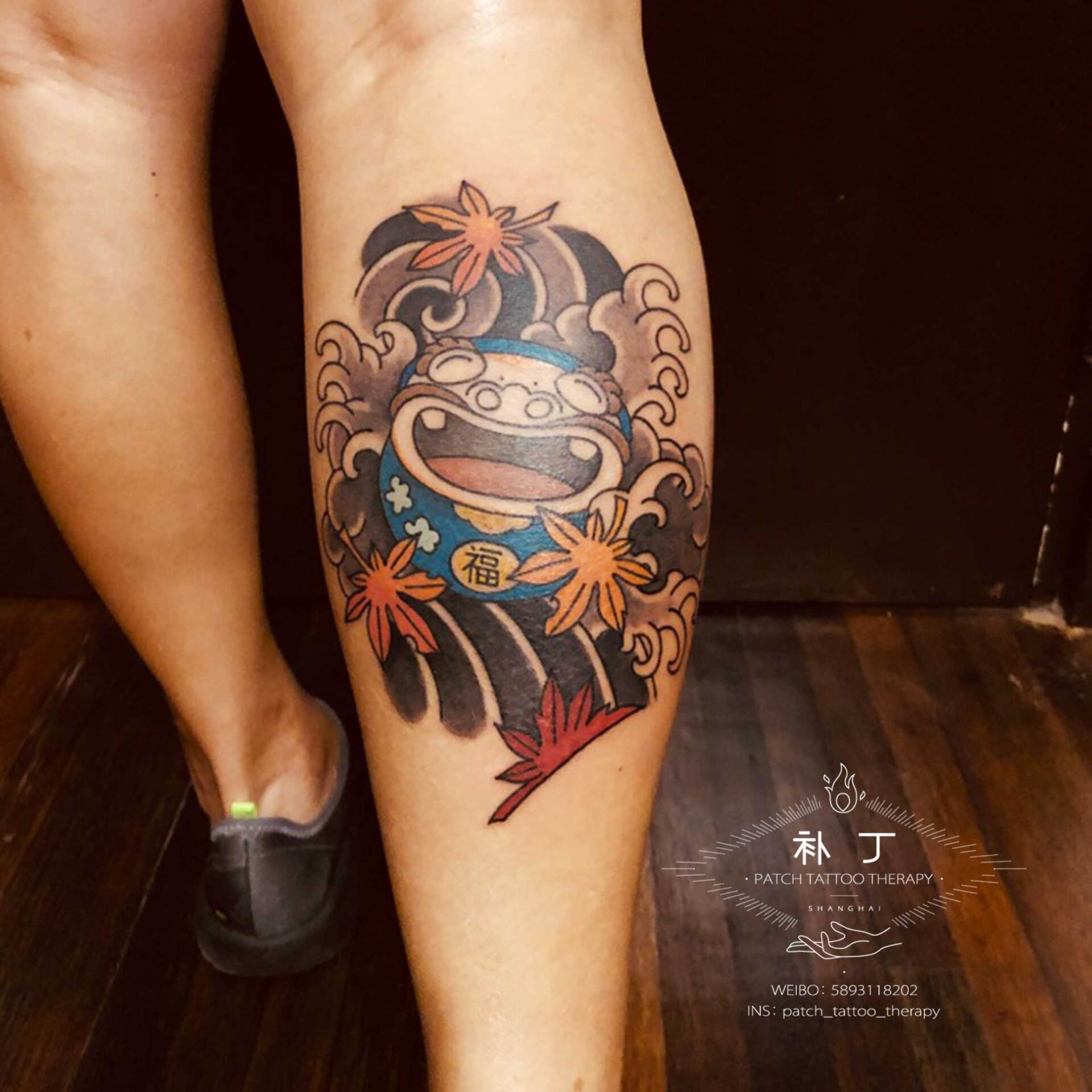 Back calf leg tattoo of a happy daruma in Japanese color style designed by Jingxi Gu at Patch Tattoo Therapy