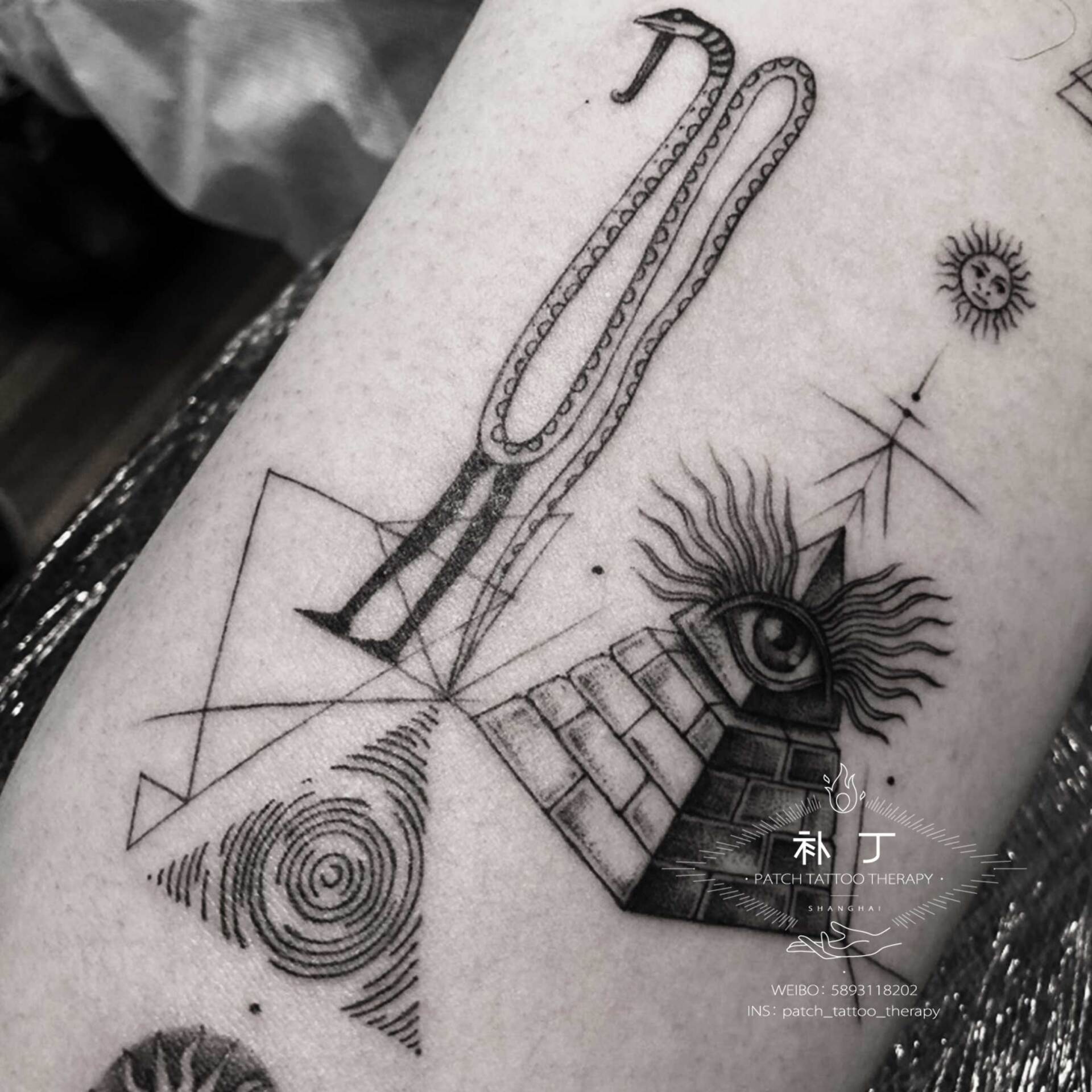 Inner arm egyptian collage tattoo featuring nehebkau the snake god, the eye of providence, the eye of horus, the sun, and a bird in geometric style designed by Jingxi Gu at Patch Tattoo Therapy - angle 2