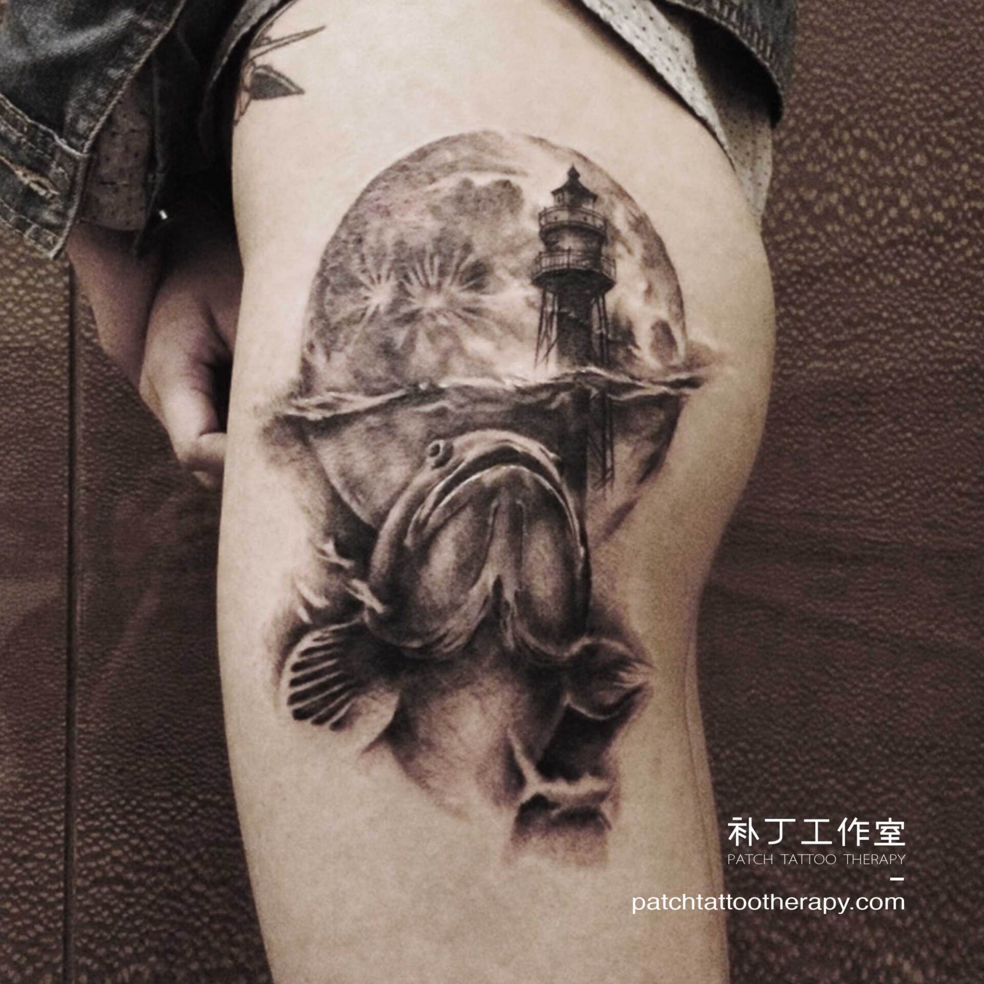 Side thigh tattoo of a fish and lighthouse in black and grey realistic style designed by Jingxi Gu at Patch Tattoo Therapy