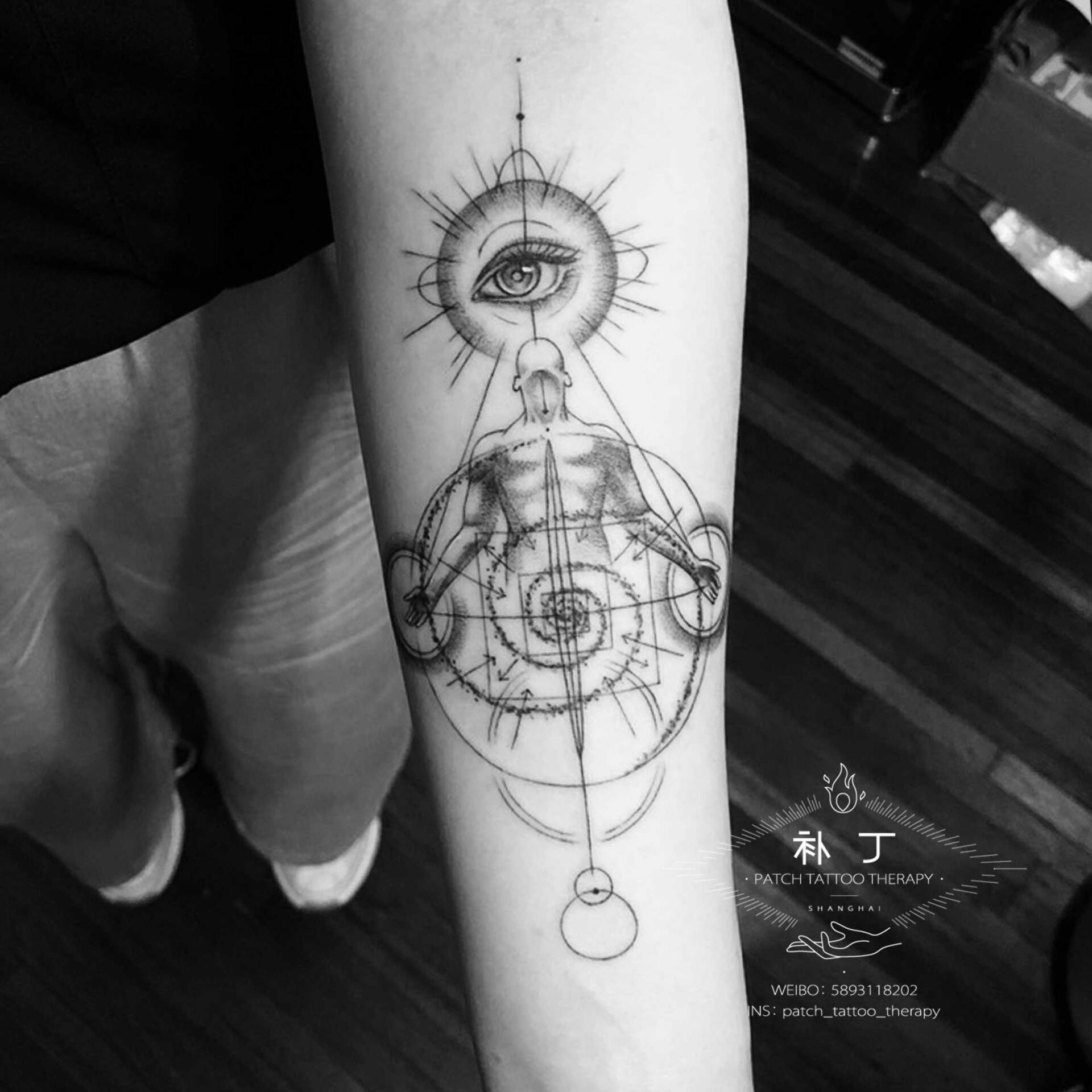 Inner forearm tattoo of a man meditating emphasizing an all knowing eye in geometric style designed by Jingxi Gu at Patch Tattoo Therapy