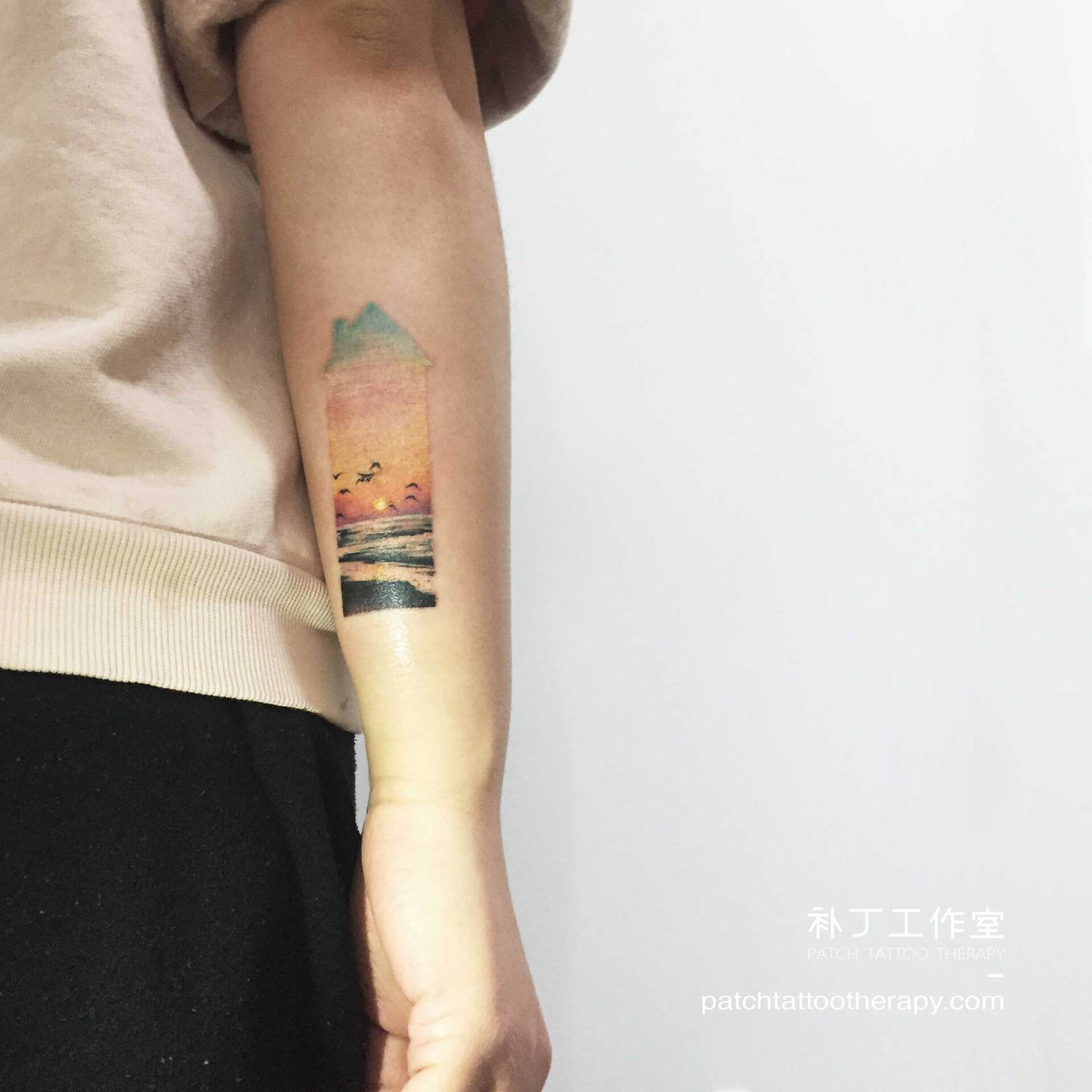 Outside forearm tattoo of the ocean with birds and sun all in the shape of a house in color micro mini style designed by Jingxi Gu at Patch Tattoo Therapy