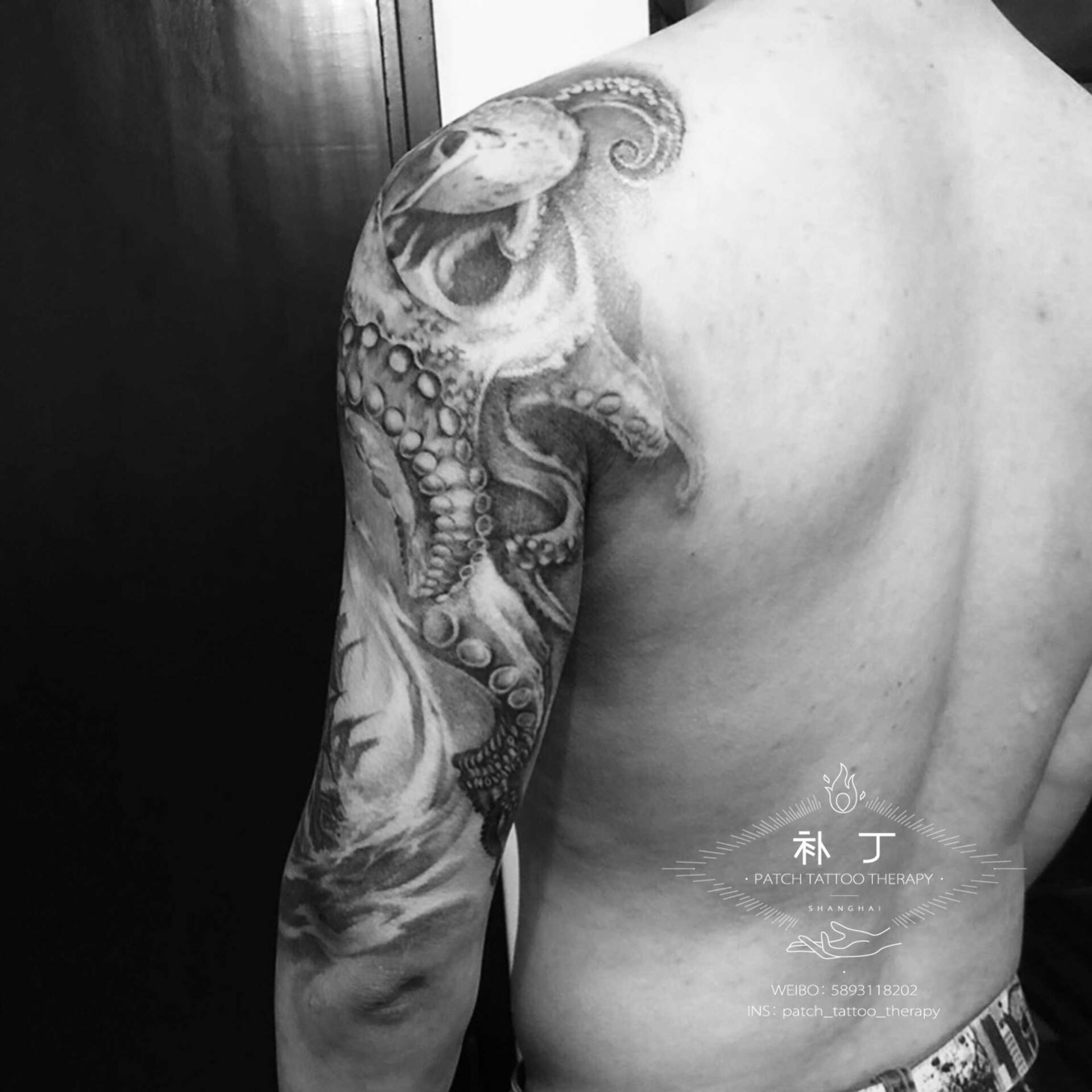 Half upper arm sleeve of an octopus, ship, and hammerhead sharks in black and grey realistic style designed by Jingxi Gu at Patch Tattoo Therapy - angle 2