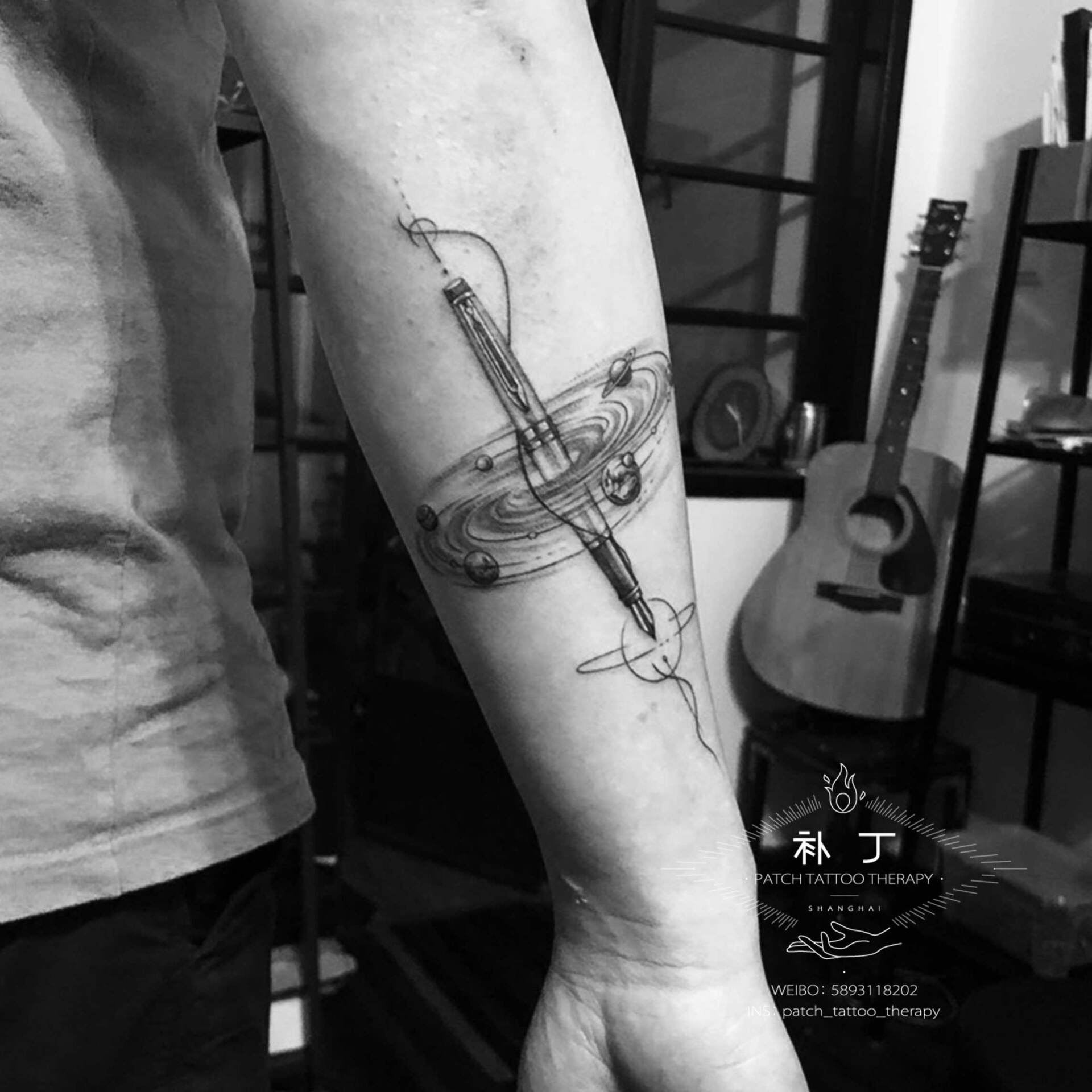 Back of forearm tattoo of a pen with the solar system spinning around it in geometric style designed by Jingxi Gu at Patch Tattoo Therapy