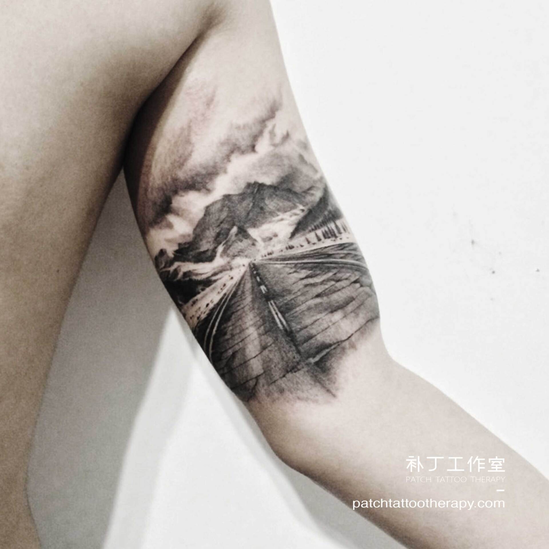 Inner arm tattoo of a road towards mountains in black and grey realistic style designed by Jingxi Gu at Patch Tattoo Therapy