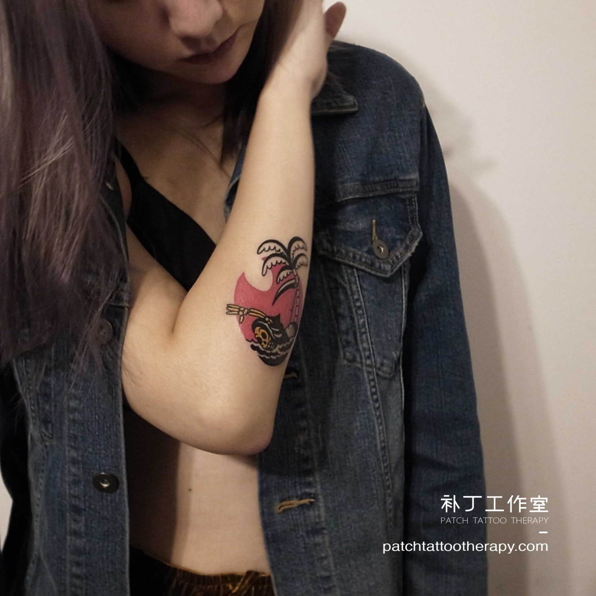 Outside forearm tattoo of a swimming skeleton with a palm tree background in traditional color designed by Jingxi Gu at Patch Tattoo Therapy - angle 2