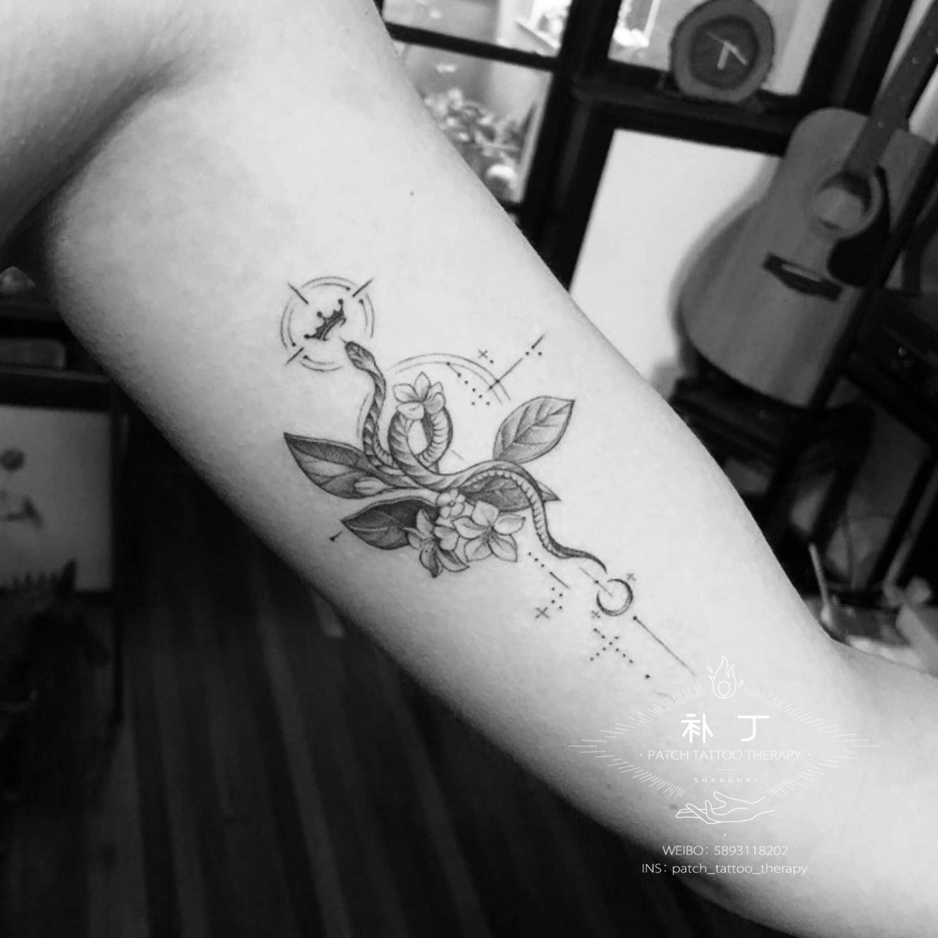 Inner arm tattoo of a snake with a crown and flowers in geometric style designed by Jingxi Gu at Patch Tattoo Therapy
