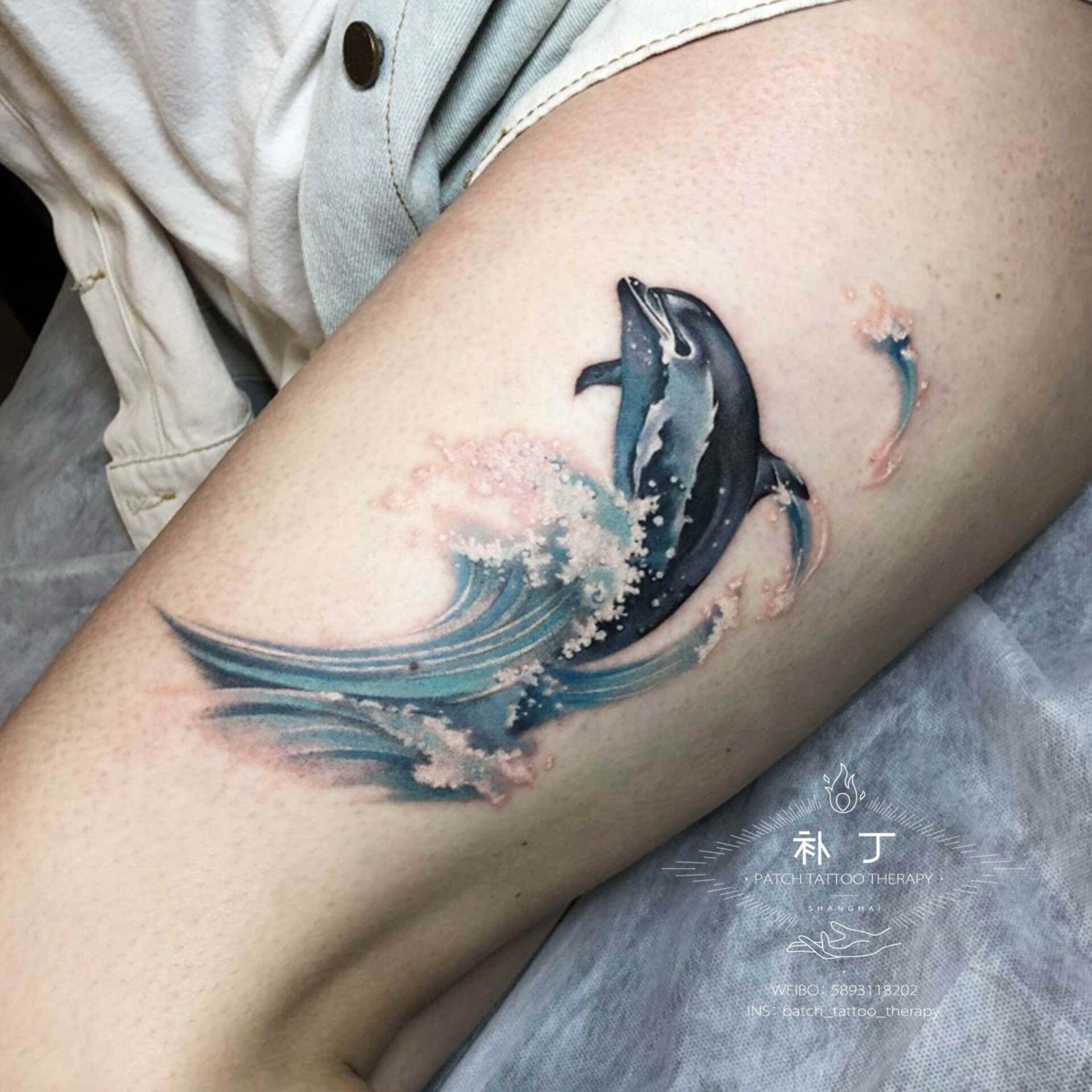 Arm tattoo of a dolphin swim jumping in micro mini color designed by Jingxi Gu at Patch Tattoo Therapy