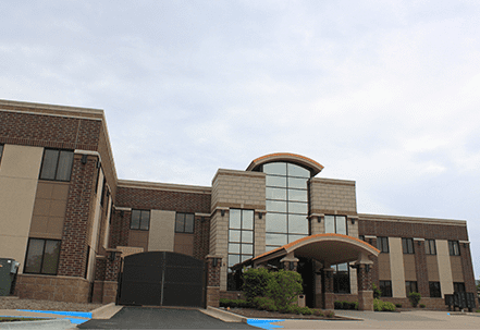 Building exterior: two-story structure with brick and beige facade under a cloudy sky.