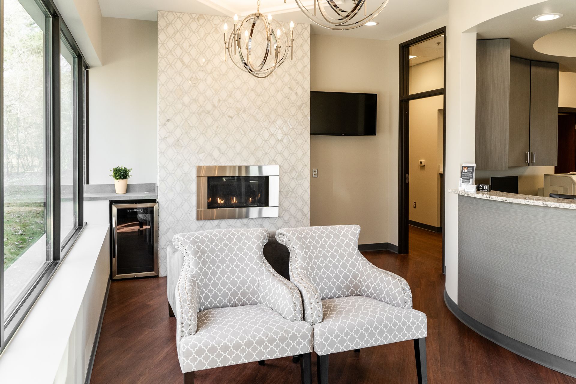 Waiting room with patterned chairs, fireplace, and drinks in a modern setting.