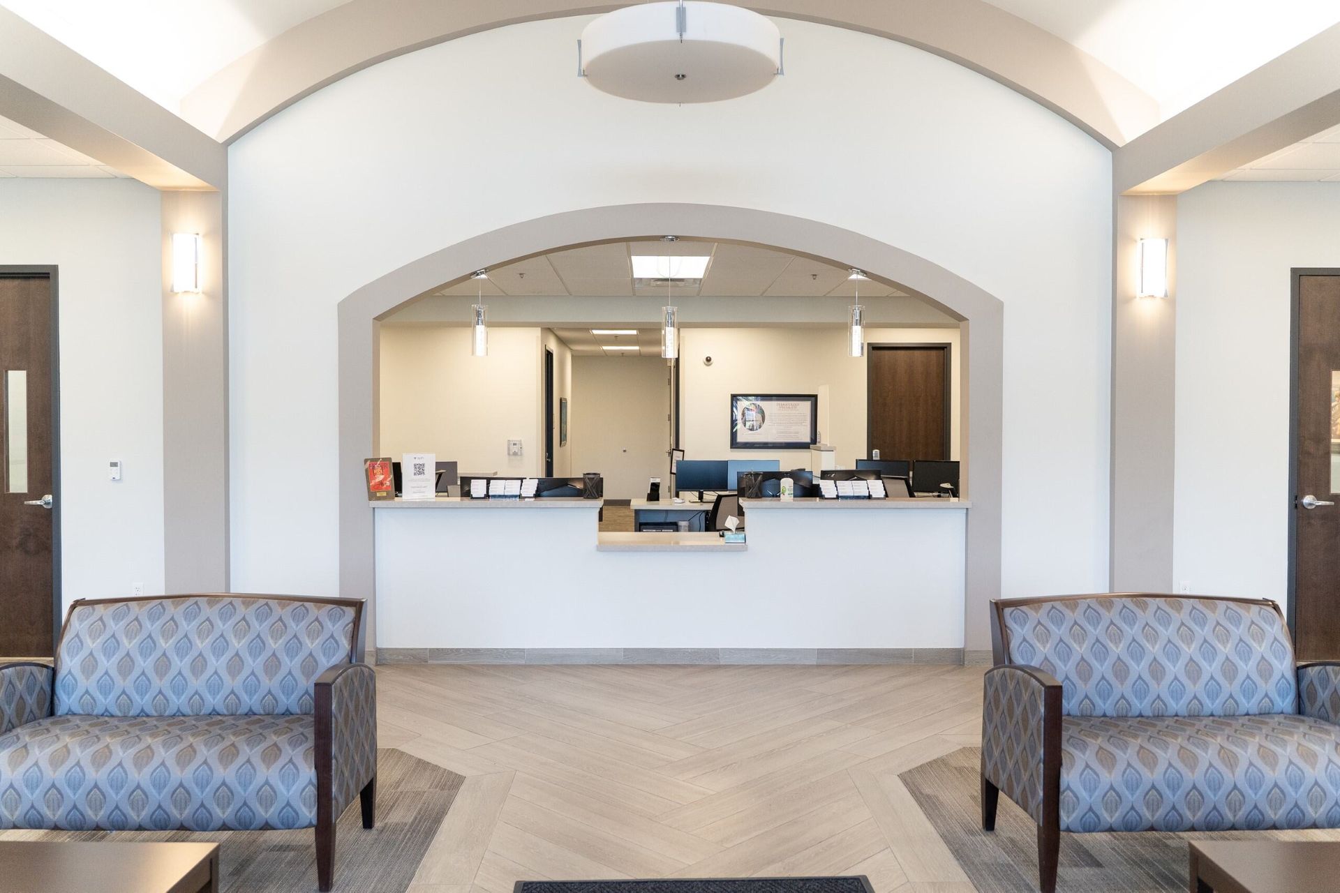 Reception area with couches, desk, and an arched opening.