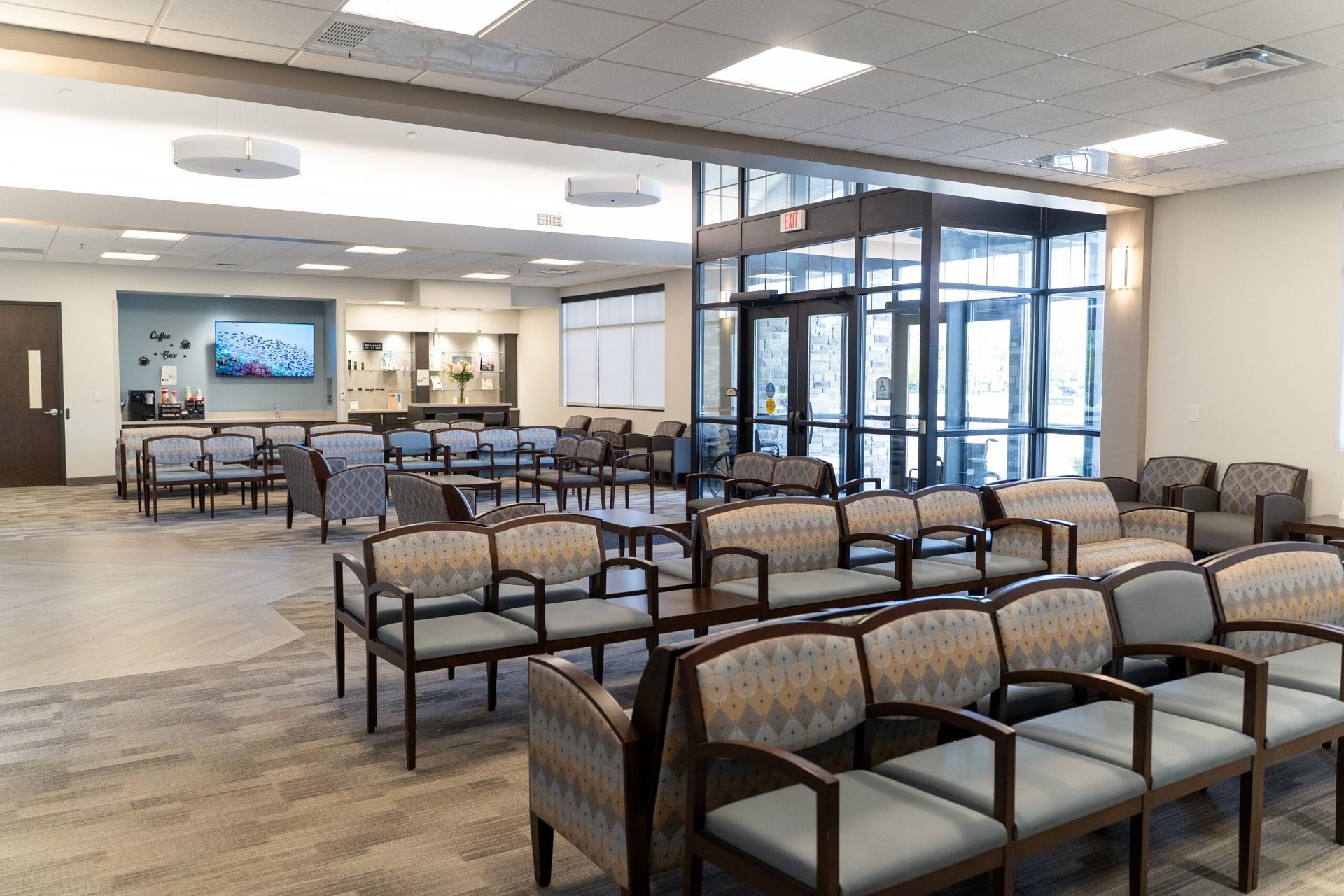 A waiting room with rows of chairs, a reception area, and an outside entrance.