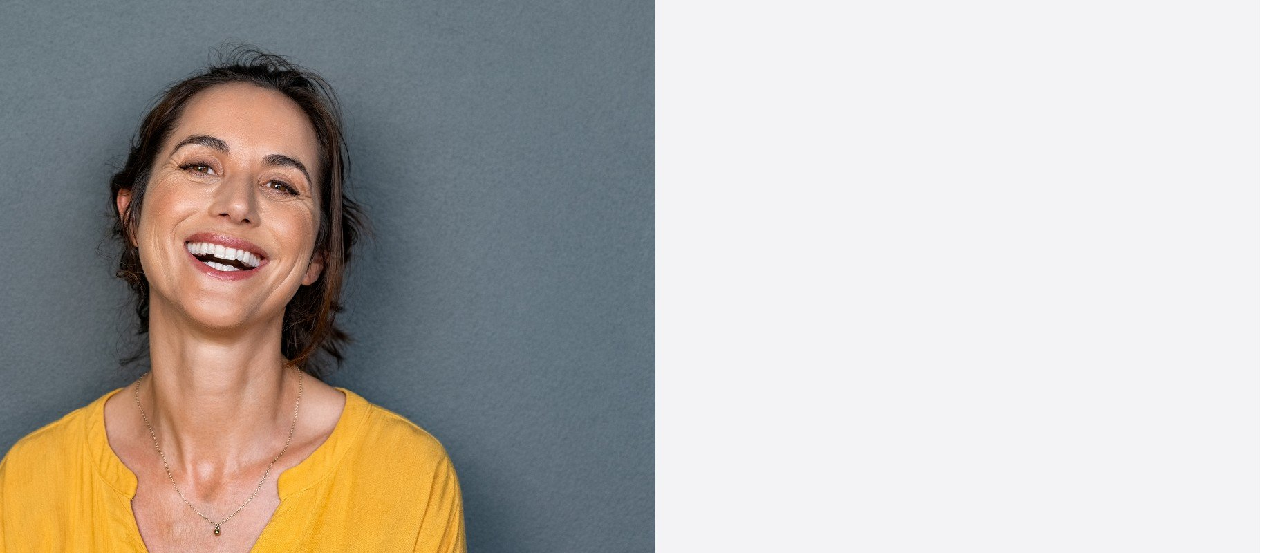 Woman laughing, wearing a yellow shirt, against a gray background.