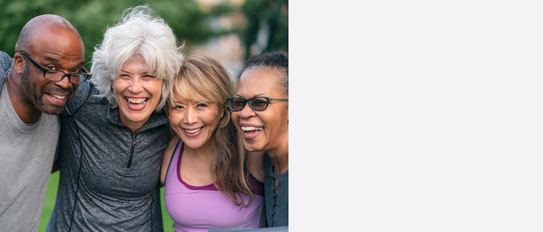 Four diverse adults laughing, embracing each other outside.