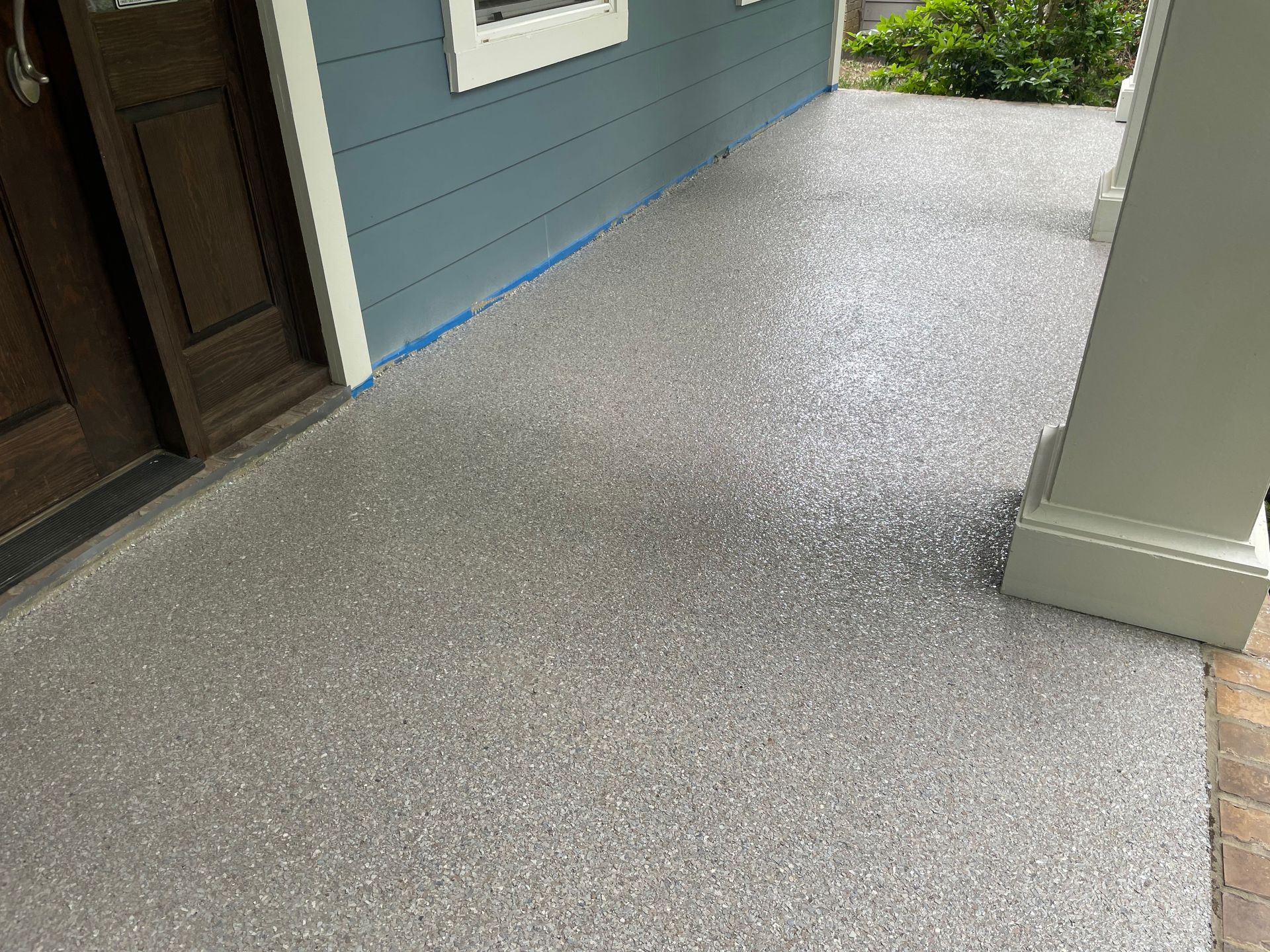 Gray speckled porch with blue siding and a white pillar.