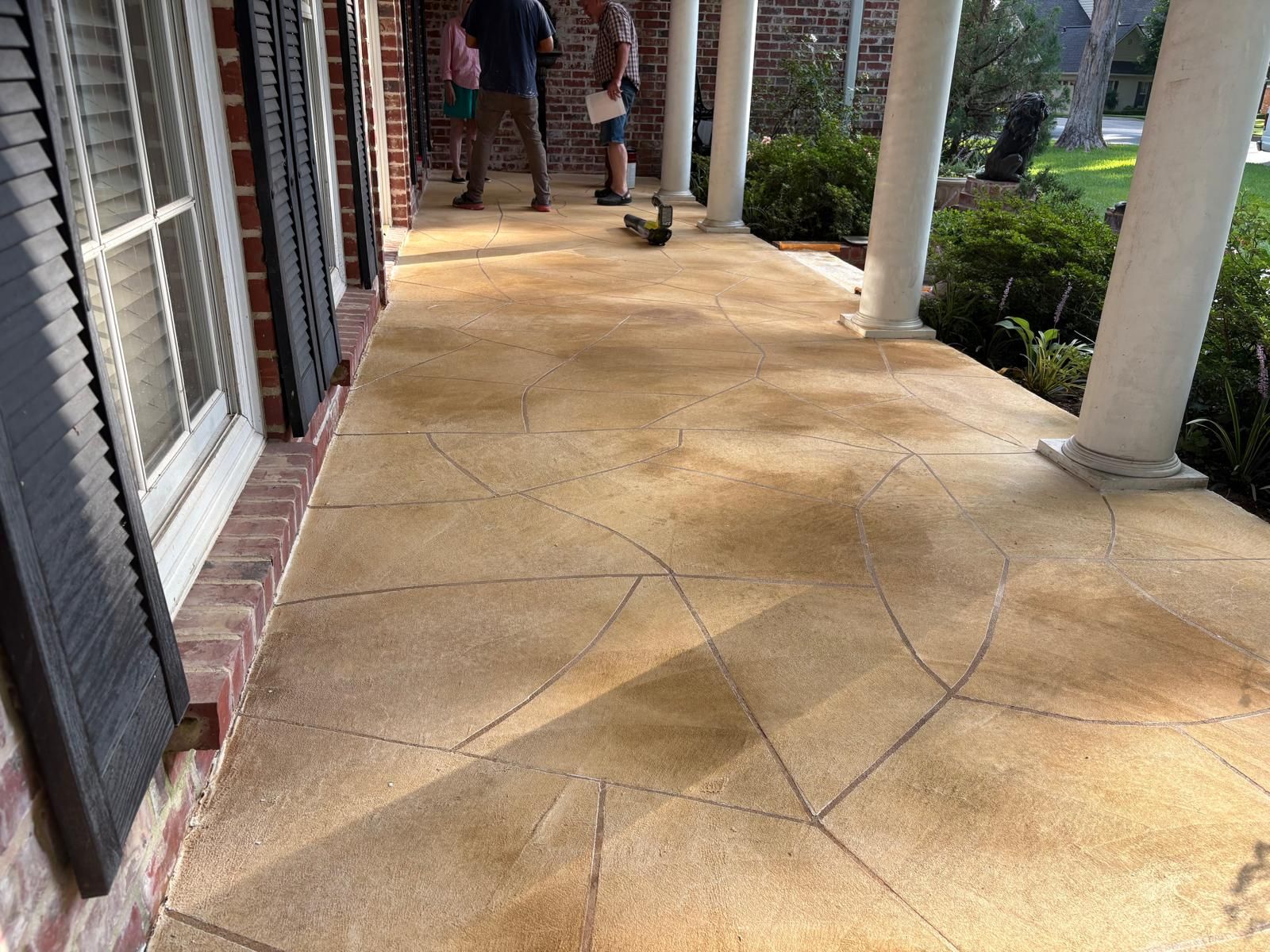 Concrete patio with curved edge; a person holds tarp near construction site.
