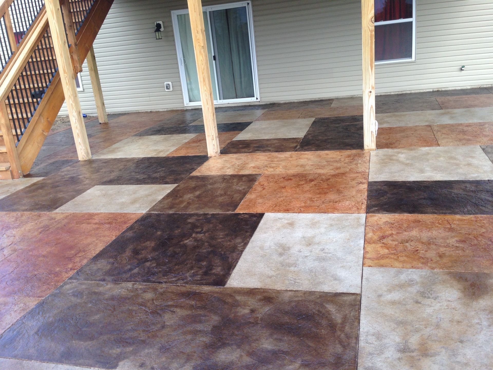 Stamped concrete porch, brown and tan, with a stone-like pattern. Columns and a water hose are visible.