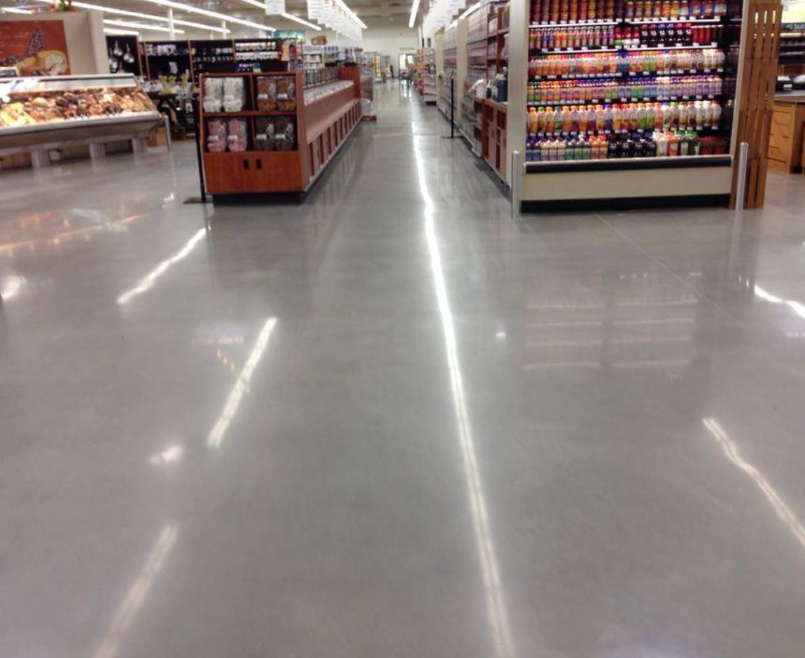 Shiny gray floor in grocery store aisle with food displays on both sides.