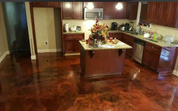 Kitchen with dark brown cabinets, island, stainless steel appliances, and a glossy, mottled brown floor.