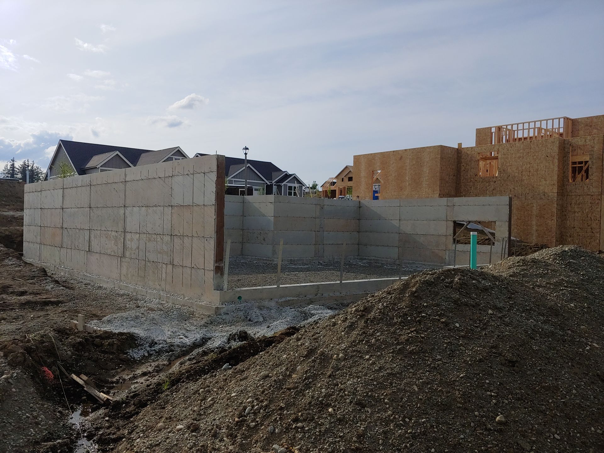 A large pile of dirt is in front of a building under construction.